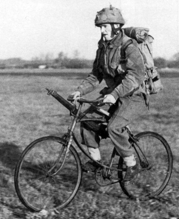 Soldado de la Segunda Guerra Mundial transportando equipo militar mientras se desplaza en bicicleta